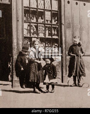 La vita per la lavorazione di folk in stile vittoriano giorni... I bambini giocando al di fuori di un negozio nella fila di Richmond, Liverpool, Merseyside England Foto Stock