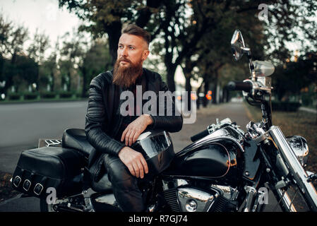Baerded biker pone sul trinciapaglia appoggiato su di un casco. Vintage bike, pilota e la sua moto, libertà lifestyle, Percorsi in bicicletta Foto Stock