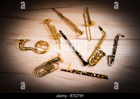 Un certo numero di toy wind instruments giacente su una tavola di legno scuro, vignette Foto Stock