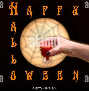Halloween biglietto di auguri o un banner, donna mano con un bicchiere di rosso liquido contro moony cerchio e spider web Foto Stock