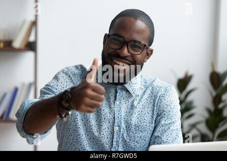 Felice dipendente mostra Thumbs up seduto alla scrivania in ufficio Foto Stock