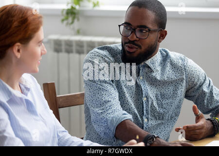 Diversi colleghi parlano seduti insieme a scrivania da ufficio Foto Stock