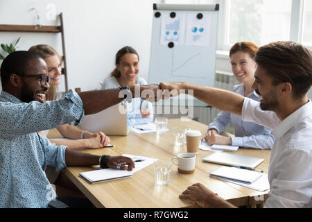 Ragazzi fist bumping congratularci gli uni con gli altri con successo sul posto di lavoro Foto Stock