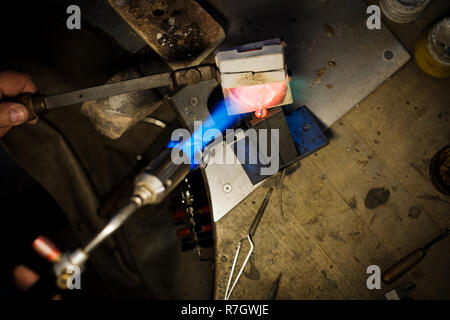 Gioielliere versamento con fuso di fiamma di oro o di argento in forma metallica al gioielliere del workshop Foto Stock