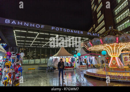 Berlino, Germania - 13 novembre 2018: la gente visita notte mercatino di Natale con la giostra su Potsdamer Platz. Ingresso alla stazione ferroviaria su uno di t Foto Stock
