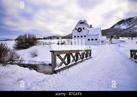 Caseificio bianco fienile con ghirlanda di Natale in un prato nevoso di Park City, UT. Foto Stock