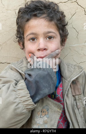 Ragazzo la cui famiglia è stata spostata dalla provincia di Helmand a causa dei talebani. Egli vive in condizioni difficili in un campo di rifugiati vicino a Kabul, Afghanistan. Foto Stock