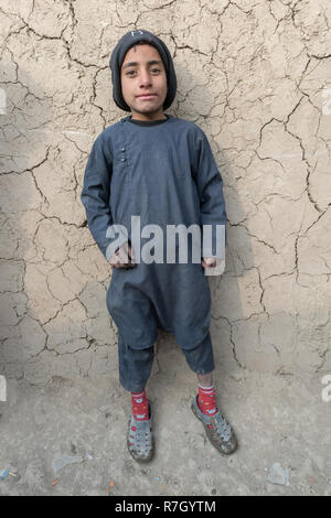 Ragazzo la cui famiglia è stata spostata dalla provincia di Helmand a causa dei talebani. Egli vive in condizioni difficili in un campo di rifugiati vicino a Kabul, Afghanistan. Foto Stock