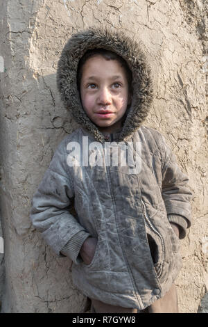 Ragazzo la cui famiglia è stata spostata dalla provincia di Helmand a causa dei talebani. Egli vive in condizioni difficili in un campo di rifugiati vicino a Kabul, Afghanistan. Foto Stock