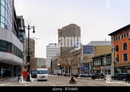 Winnipeg, Manitoba, Canada - 2014 11 17: una persona in sedia a rotelle attraversate l'incrocio di Portage ave e Smith st d'inverno. Foto Stock