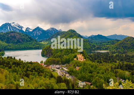 Grande vista panoramica del castello di Hohenschwangau nel centro accanto al villaggio di Hohenschwangau, con il lago Alpsee sul lato sinistro, il lago Schwansee... Foto Stock