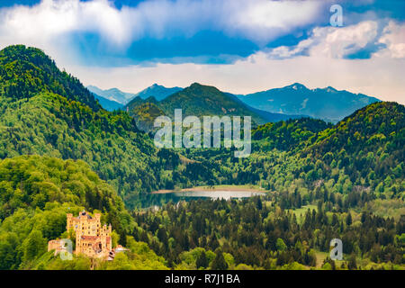 Bellissima vista del paesaggio del Castello di Hohenschwangau e il lago Schwansee circondato da una foresta e sullo sfondo le Alpi. Il castello si trova vicino al ... Foto Stock