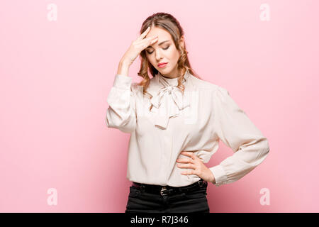 Grave infelice femmina ha aspetto accattivante, essendo triste dopo litigare con la persona vicina, acciglia faccia in insoddisfazione, isolato su rosa di sfondo per studio. Umano emozioni negative concept Foto Stock