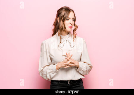 Grave infelice femmina ha aspetto accattivante, essendo triste dopo litigare con la persona vicina, acciglia faccia in insoddisfazione, isolato su rosa di sfondo per studio. Umano emozioni negative concept Foto Stock