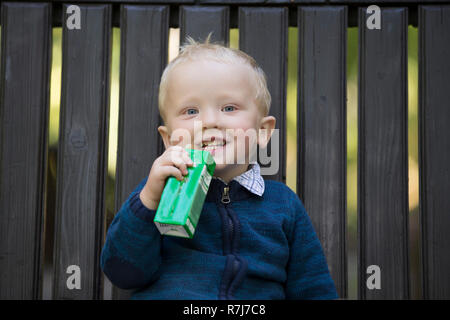 Il bambino è di bere succo di frutta dal tubo per una passeggiata Foto Stock