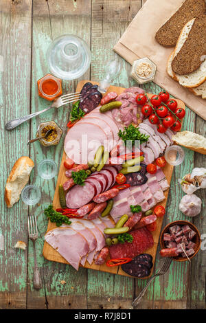 Un assortimento di salsicce e carne affumicata con sottaceti, pane e vodka sulla tavola di legno, vista dall'alto uno spazio di copia Foto Stock