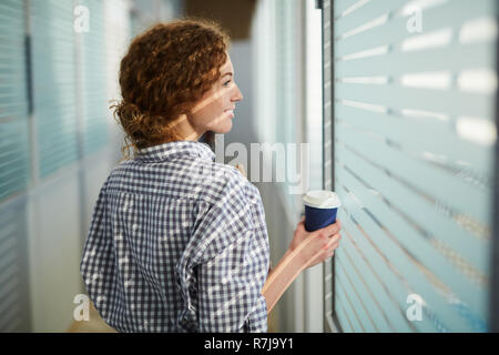 Designer positivo camminando nel corridoio stretto di ufficio della società Foto Stock