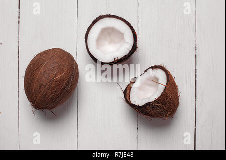 Noci di cocco su un bianco sullo sfondo di legno. Frutta esotica Foto Stock