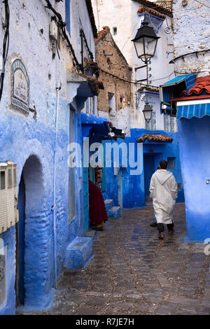 Il Marocco, Chefchaouen, la città blu, medina, Calle Jarazin, uomo che indossa jellaba camminando attraverso la strada stretta della Città Vecchia Foto Stock