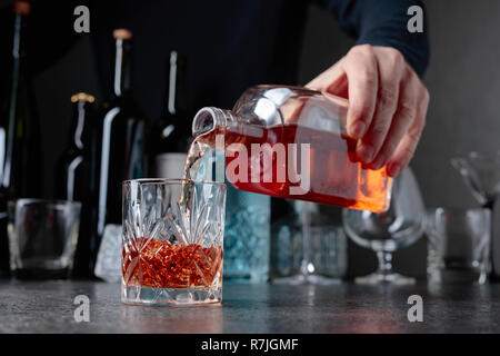 Barman in grembiule aggiunge l'ingrediente al vetro Foto stock - Alamy