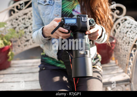 Close-up di mani femminili in possesso di una fotocamera professionale. Fotografo femmina con una telecamera professionale. Foto Stock