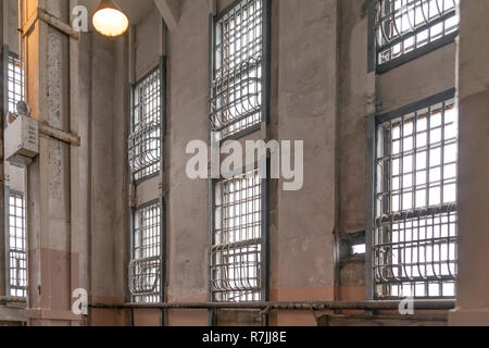 Vecchio penitenziario di correzzione jailhouse parete multilivello di windows coperto con acciaio solido verticali e barre orizzontali dipinte in toni neutrali. Foto Stock