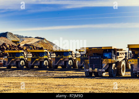 Giallo grande dumper mettere in fila nella miniera a cielo blu con nuvole in background Foto Stock