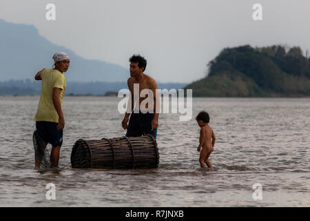 Don Daeng, Laos - Aprile 27, 2018: due uomini e un bambino per la cattura di pesce al tramonto in una remota isola del fiume Mekong in Laos Foto Stock