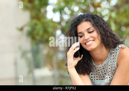 Lady felici parlando su smart phone seduto in un parco Foto Stock