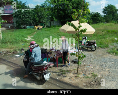 Femmina motociclista vietnamita si è fermato a lato della strada a comprare carne da una banchina di stallo Asia Vietnam Foto Stock