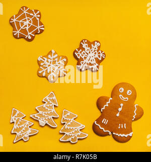 Gingerbreads nelle forme di fiocchi di neve, di alberi di natale e cookie uomo brillante su sfondo giallo Foto Stock