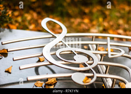 Silver Chrome clef con music bar su un monumento con foglie di autunno Foto Stock