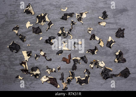 Sacco di fette di secco fungo nero ebreo orecchio varietà flatlay sulla pietra grigia Foto Stock