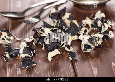 Sacco di fette di secco fungo nero ebreo orecchio varietà su legno marrone Foto Stock