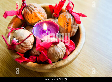 Candela viola con wallnuts decorate in una ciotola di legno. Per Natale e la celebrazione del Capodanno cinese Foto Stock
