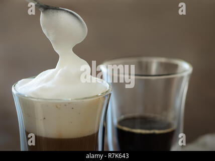 Schiuma di latte viene messo in un bicchiere di caffè. Foto Stock