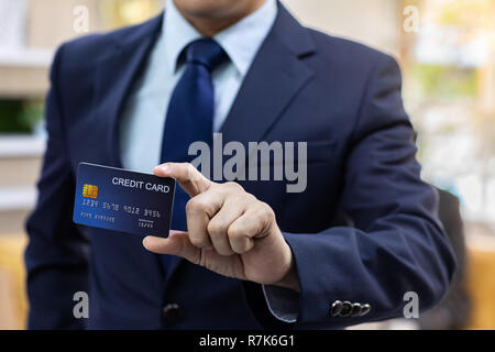 Primo piano di imprenditore tenere la sua carta di credito per effettuare un pagamento Foto Stock