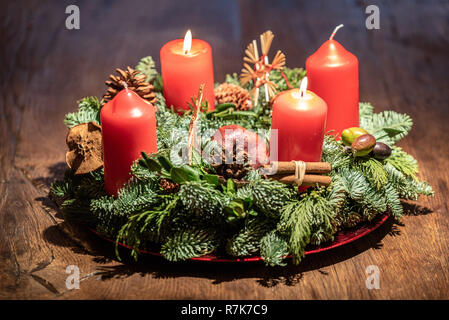 Corona di avvento e la masterizzazione di due candele rosse su un tavolo in legno Studio Foto Stock