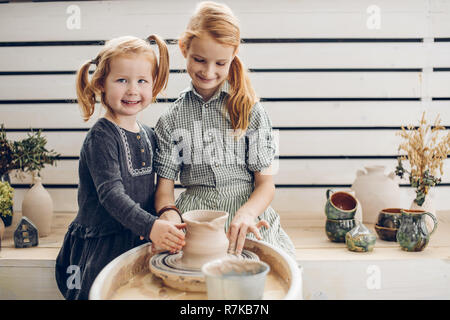 Sorridente i capelli rossi i bambini utilizzando la ruota in ceramica Foto Stock