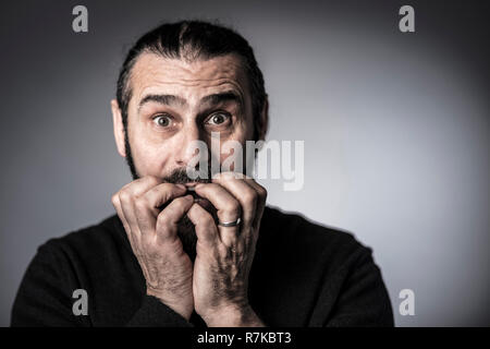 Scary uomo coprire la bocca con le mani studio shot Foto Stock