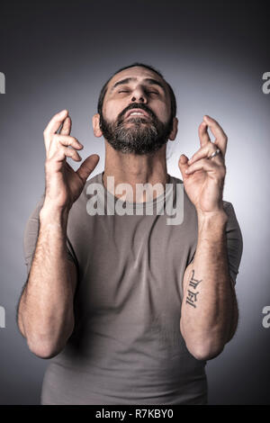 Ritratto di uomo caucasico attraversando il dito con gli occhi chiusi Foto Stock