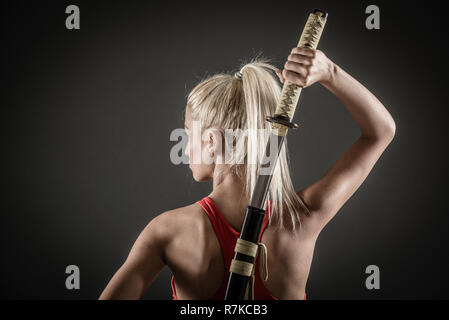 Bella ragazza con un espressione seria sul suo viso katana di disegno. Foto Stock