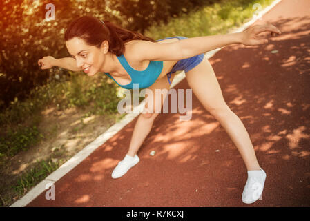 Felice giovane bella donna facendo esercizio in tartan via in una giornata di sole. Foto Stock
