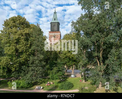 I giovani in seduta Tuomiokirkonpuisto (Cattedrale Park) nella luce del sole serale con la cattedrale di Turku (Turun tuomiokirkko) dietro, Turku, Finlandia Foto Stock