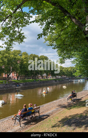 La gente seduta sulle sponde del fiume Aura (Aurajoki) nel centro storico, Turku, Finlandia Foto Stock