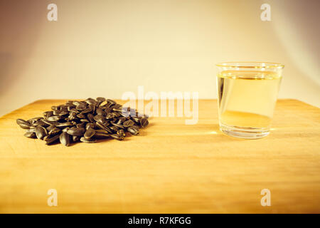Una manciata di semi di girasole, olio di semi di girasole in un bicchiere sul tavolo. Foto Stock