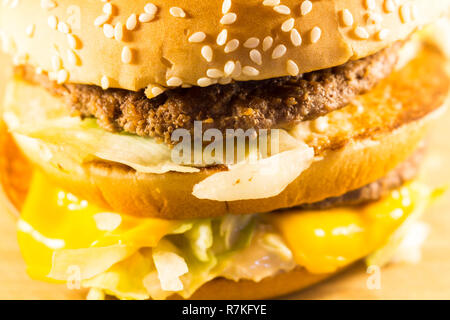 Big burger con due cotolette, formaggio e insalata. Vista laterale Foto Stock