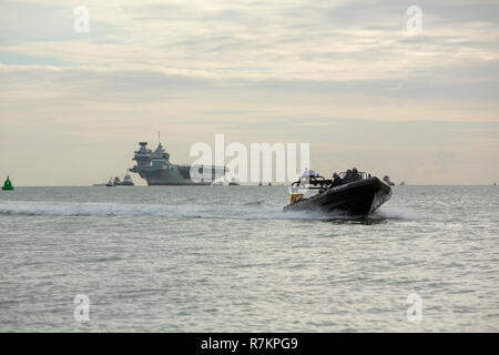 Il porto di Portsmouth, Regno Unito. 10 dic 2018. HMS Queen Elizabeth arriva a casa a Portsmouth per Natale. Barca di polizia controllando il modo in cui è sicuro di davanti del veicolo. Credito: David Robinson/Alamy Live News Foto Stock