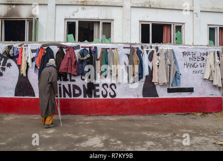 Dicembre 10, 2018 - Srinagar, Jammu e Kashmir India - un disabile vecchio uomo guardando i vestiti appesi al muro di gentilezza in Srinagar.Per prendersi cura di senza tetto e di bisognosi di persone durante gli inverni, Volontarii in Srinagar hanno iniziato a lavorare per dipingere le pareti e trasformandole in ''˜parete di gentilezza" in tutta la città. Il tema di questa iniziativa è quello di dare a coloro che sono nel bisogno. Angolo di carità invita i passanti con uno slogan, ''˜lasciare ciò che non è necessario' e ''˜prendere se avete bisogno di credito: Idrees Abbas SOPA/images/ZUMA filo/Alamy Live News Foto Stock