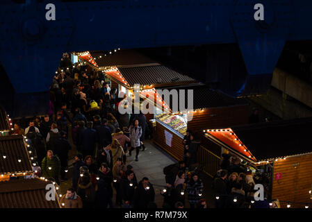 Mercatino di Natale di notte con le luci sulla South Bank di Londra, Regno Unito. Gli amanti dello shopping. Southbank, Queen's Walk, sotto il ponte a Hungerford, Lambeth. Cabine Foto Stock